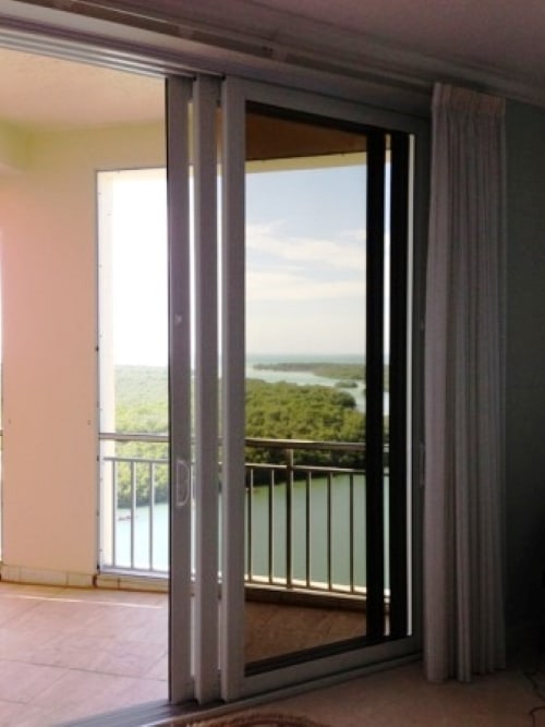 Professional installing impact sliding glass doors on Marco Island home