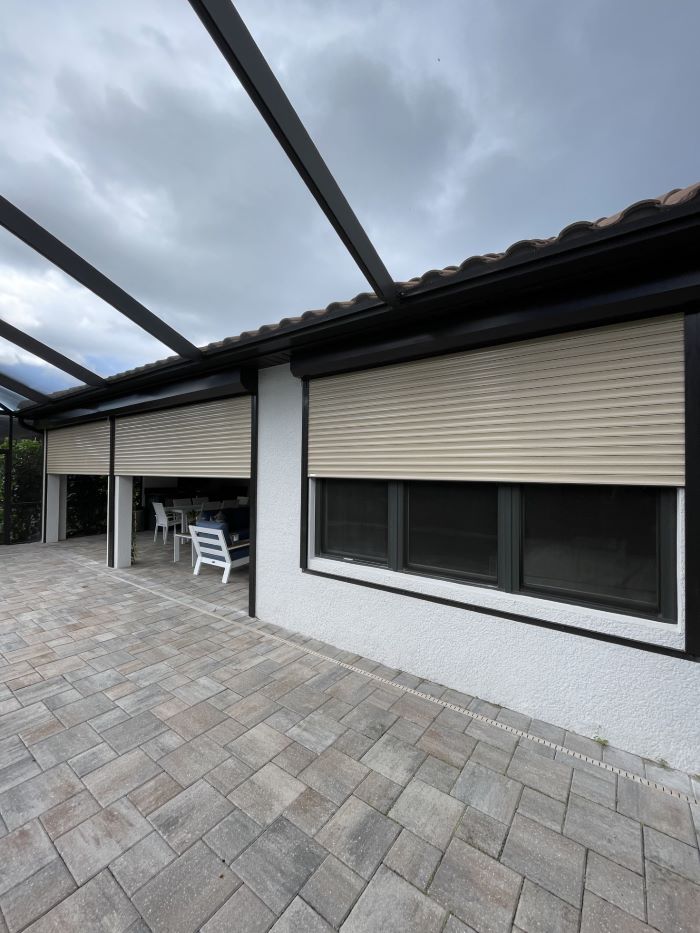 Custom motorized roll-down shutters protecting Marco Island waterfront property from hurricane winds